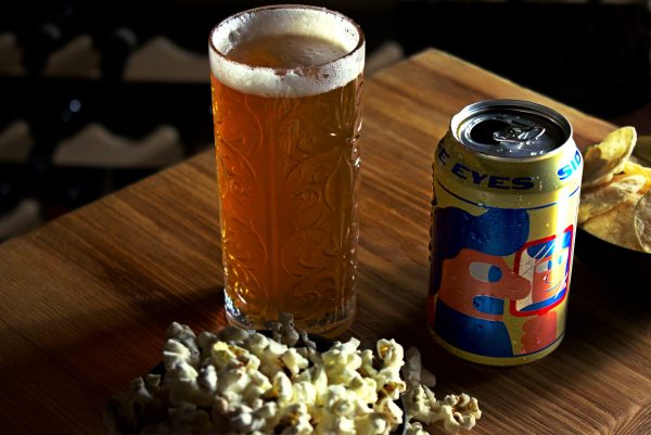 Mikkeller Side Eyes Beer In A Glass With Popcorn And Chips
